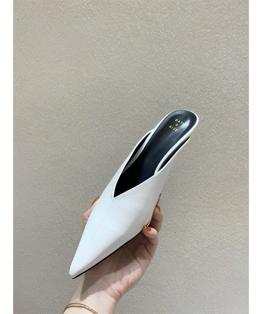 手に持ったホワイトのVカットミュール。シャープなつま先と滑らかな質感