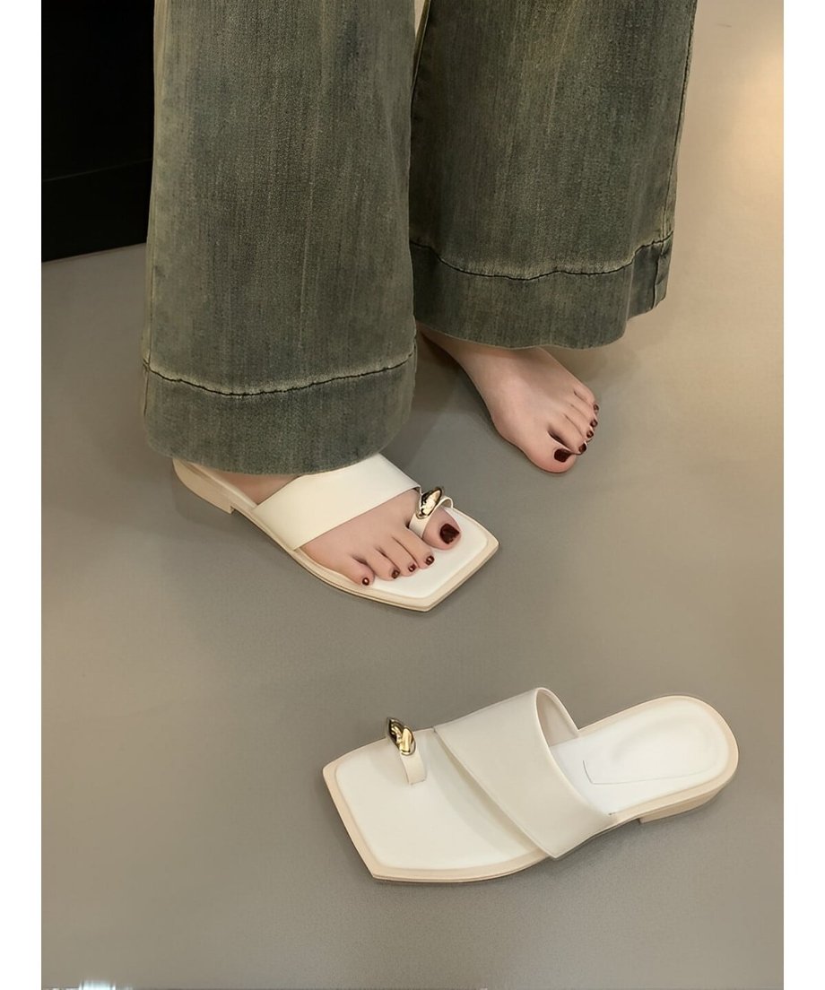 ホワイトのサンダルをワイドパンツに合わせて着用した足元の写真。片方だけ履いている。トレンド感のあるスクエアトゥのシルエット。