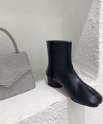 クリスタルが施されたハンドバッグの横に片足のスプリットトゥの足袋ブーツ。