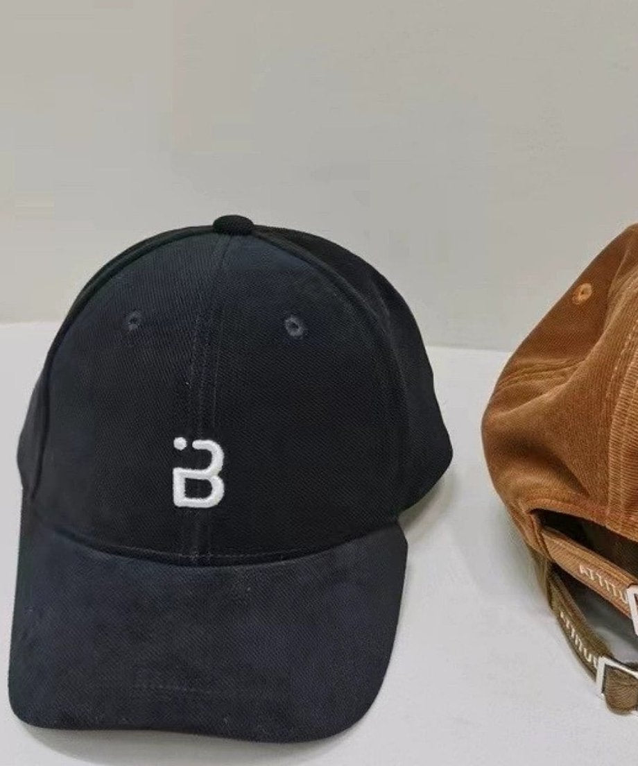 黒いコーデュロイキャップのフロントに、ユニークな形状のBの文字が白く刺繍されています。