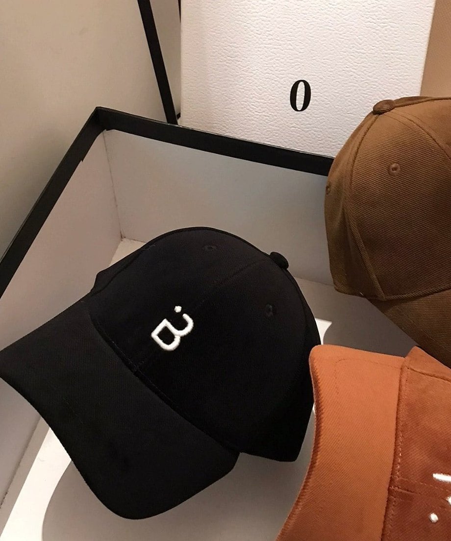 ブラックのキャップ。フロントにBの刺繍があり、バックベルトの白いロゴデザインがアクセント。横にダークブラウン、キャメルのキャップが見える。