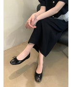黒のスパンコールバレエシューズをはいた女性が椅子に座り足を組んでいるショット。