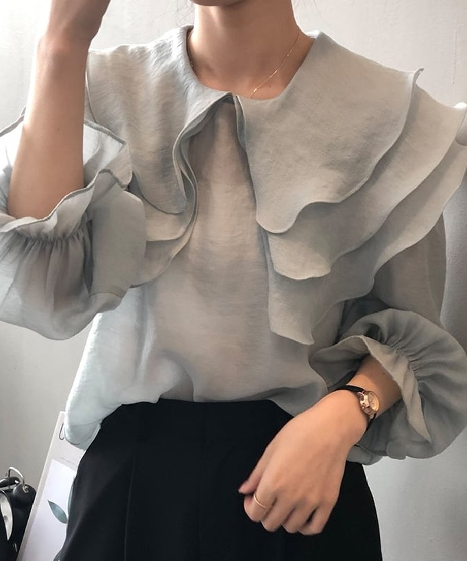ブルーのブラウスを着用した女性を正面から撮影。袖のふくらみとフリルの重なりを表現。