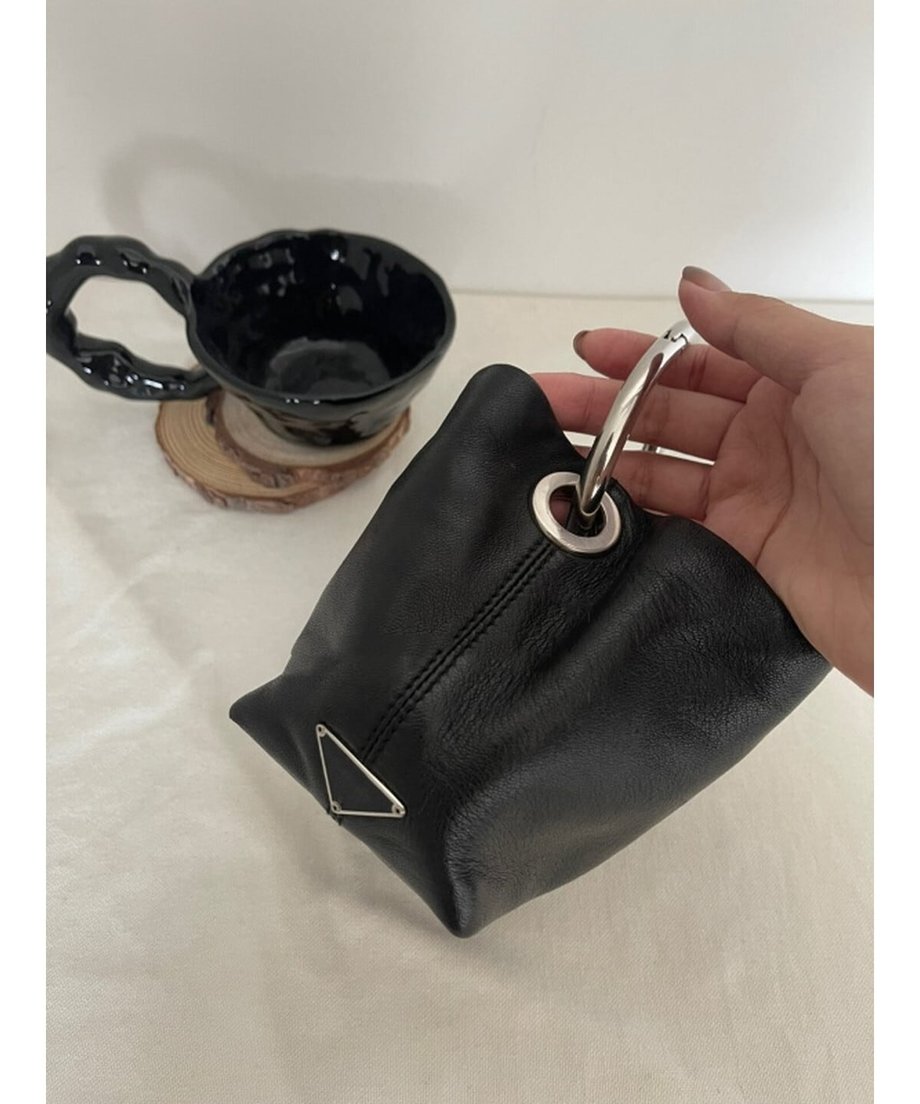 黒いカップが置かれたテーブルの上で、手首にリングハンドルを通してバッグを持つ様子。