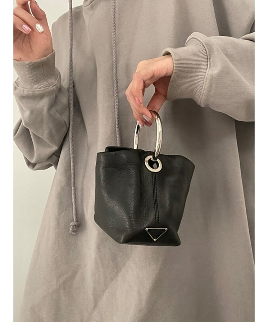 グレーのパーカーを着た女性が、シルバーのリングハンドルが付いた黒のPUレザーミニバッグを手に持っている様子。