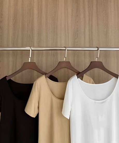 ハンガーに掛けられたブラック、ベージュ、ホワイトの3色のバックオープンTシャツ。背中の開き具合が比較できる。