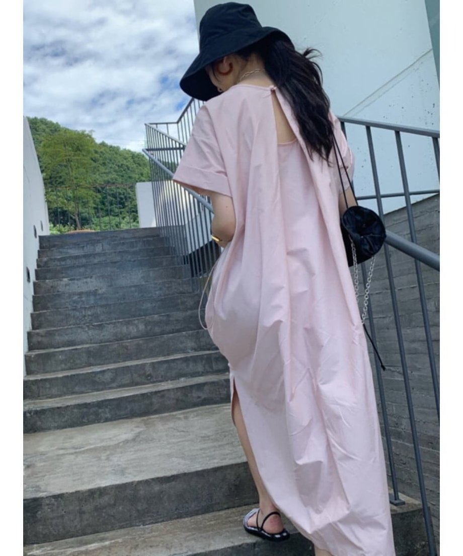 ピンクのワンピースとブラックのバケットハットを合わせた女性が階段を上るバックショット。