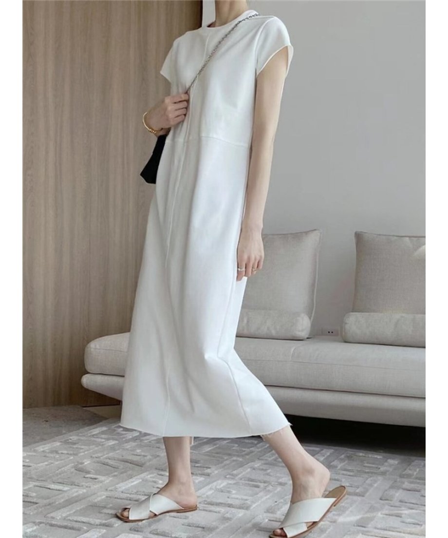 白いセンターシームドレスを着用し、白いフラットサンダルで歩く足元のカット