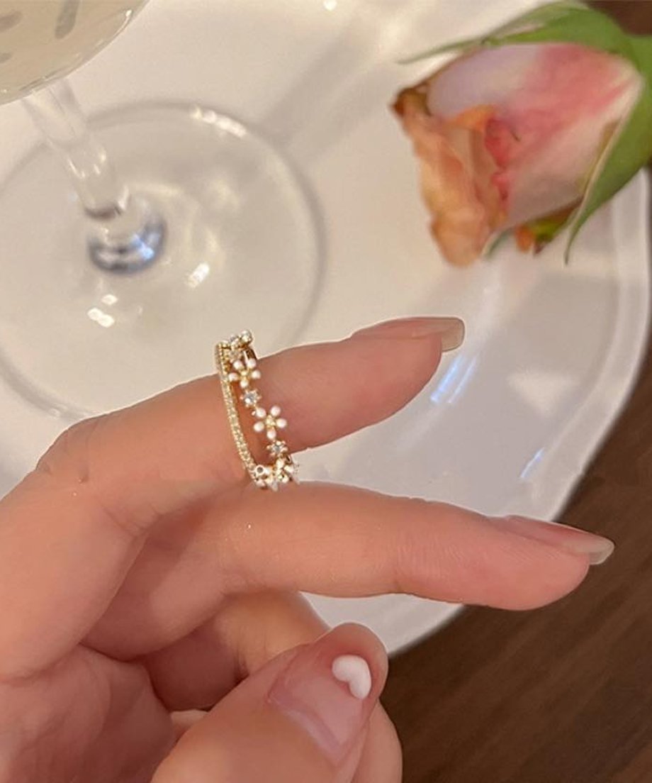 指先にフィットする華奢なフラワーモチーフのゴールドリングを横から捉えたクローズアップ写真