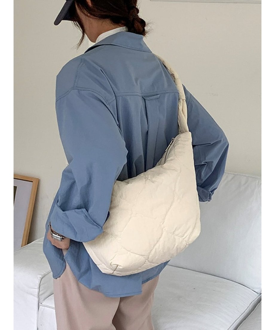 ホワイトのキルティングショルダーバッグを背中側へ回して肩掛けしている女性の後ろ姿。