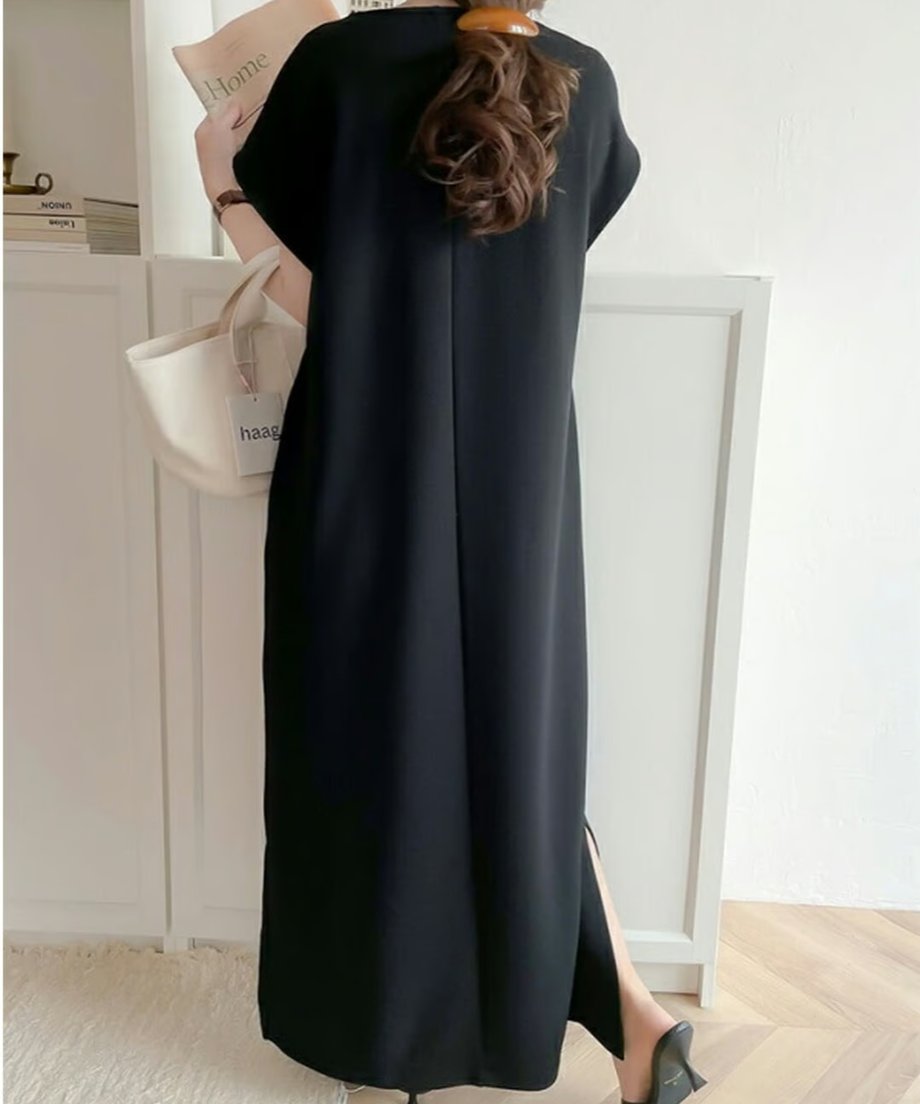 髪を束ねた女性が黒のロングワンピースを着用し、背面から見たシルエット