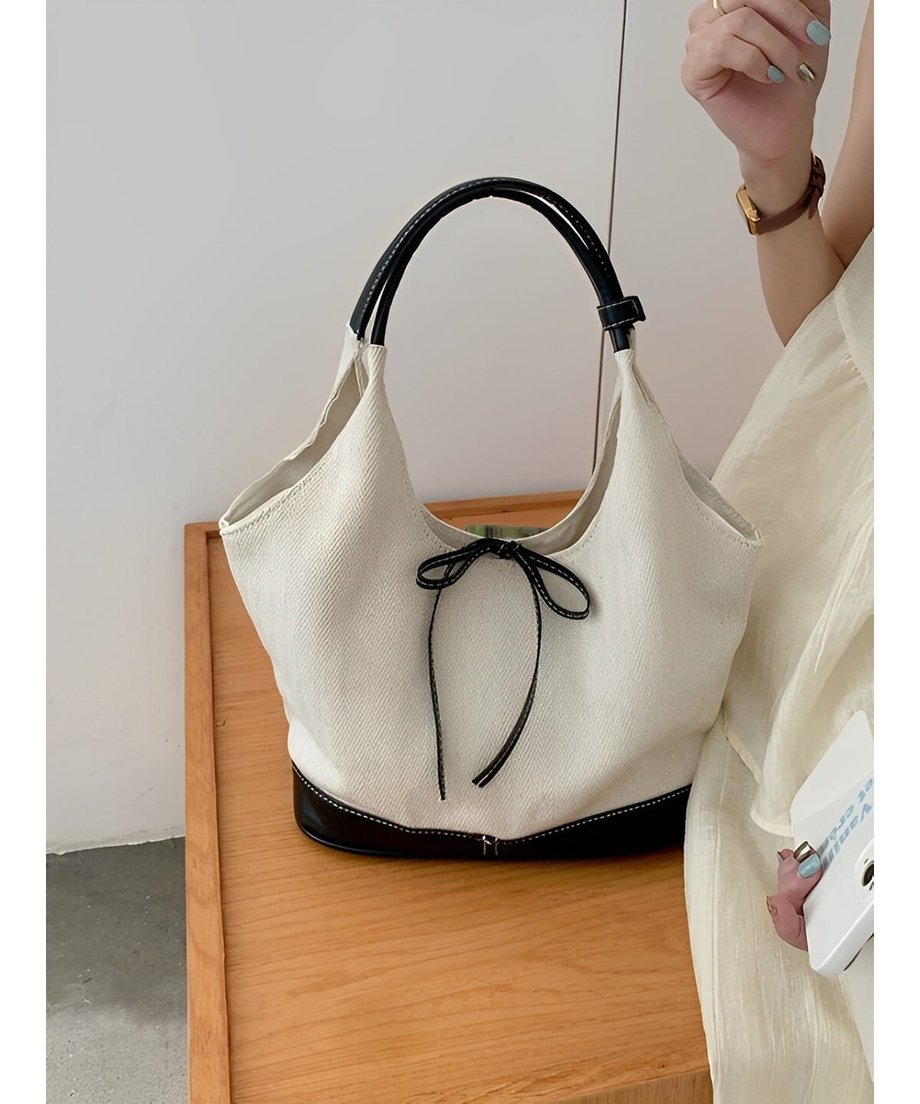 木製のテーブルの上に置かれた、ステッチ入りのリボンが目を引くキャンバストートバッグ。