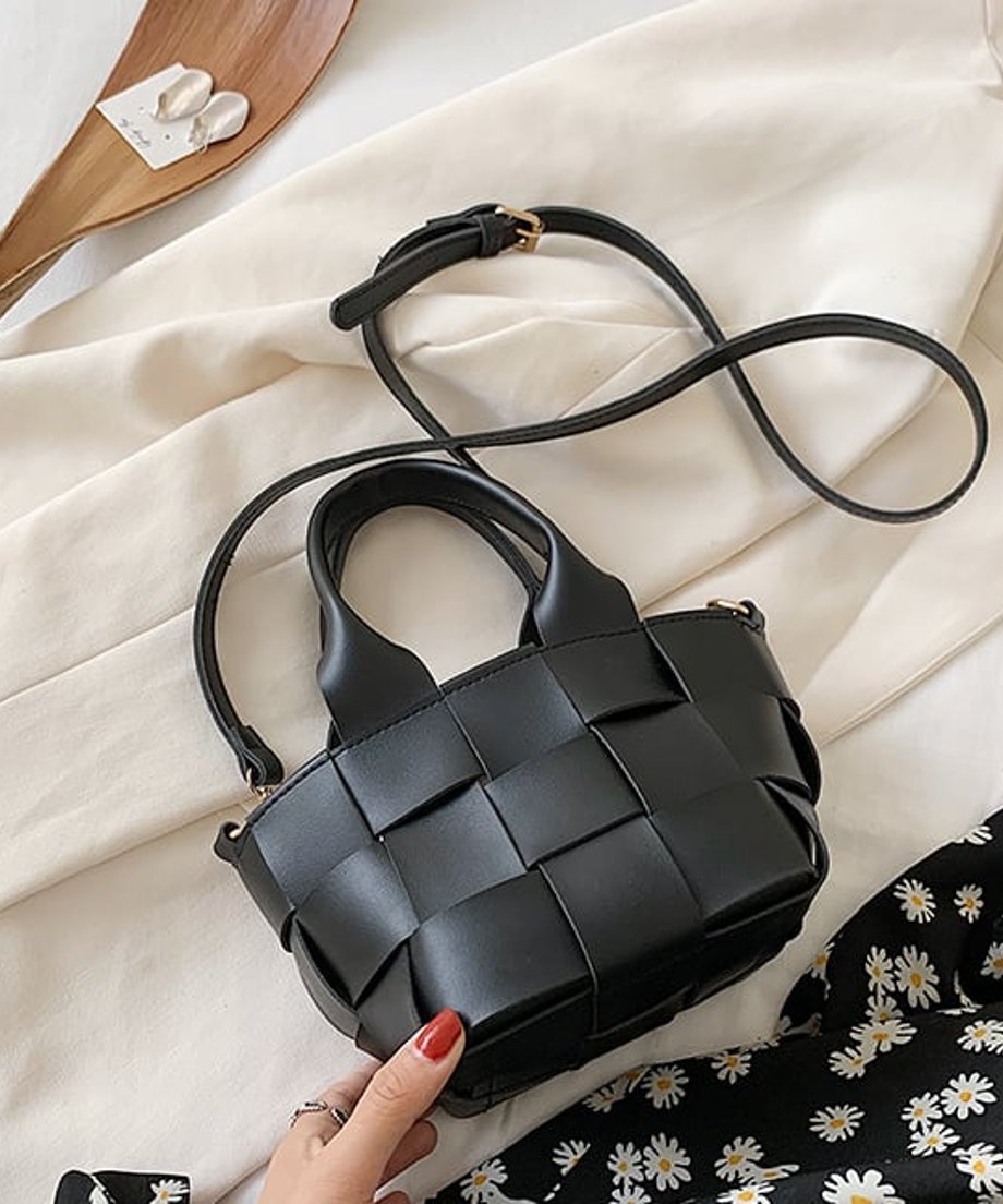 手に持った黒色のメッシュミニバッグ。太めの編み込みデザインとゴールドの金具が特徴。