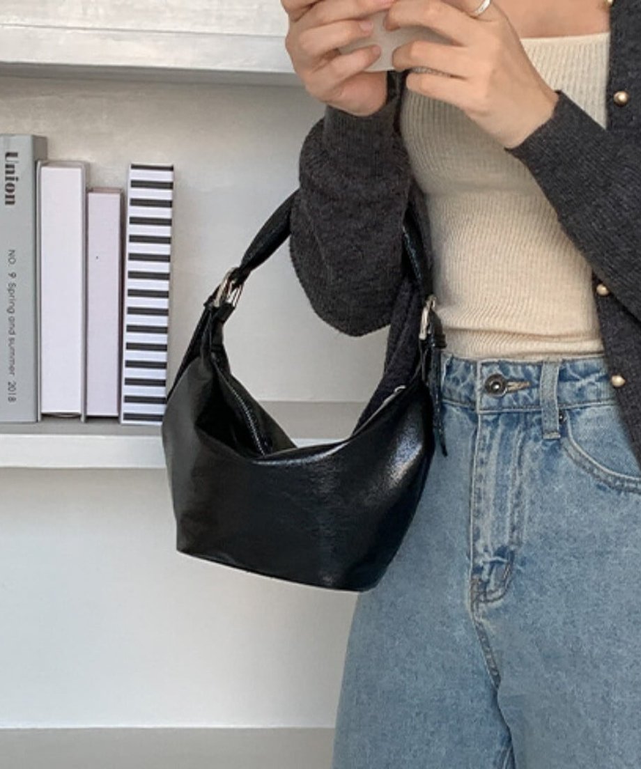黒のミニバッグを腕にかけて持つ女性のスタイリング。
