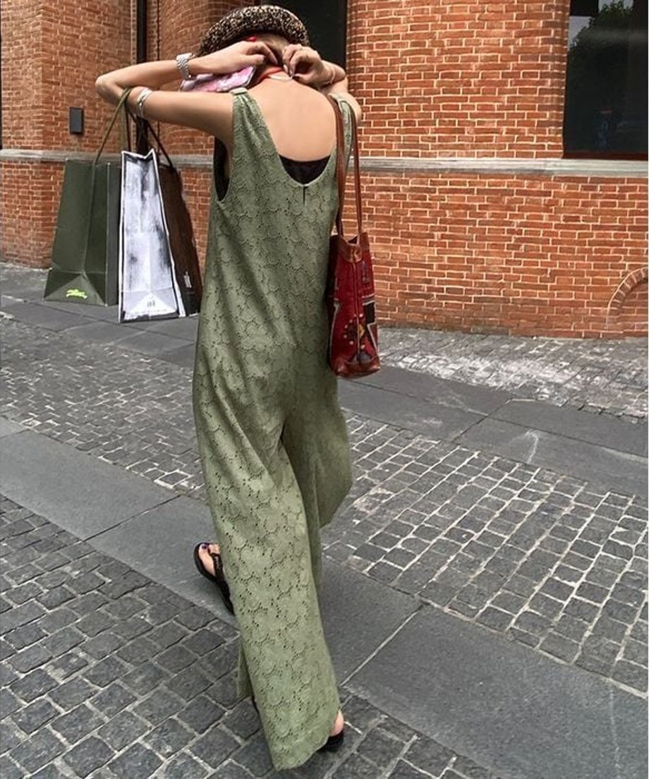 ストローハットとグリーンの刺繍入りオールインワンを合わせた女性のバックショット。
夏を歩くゆったりとしたパンツ部分のドレープ感がわかるカット。