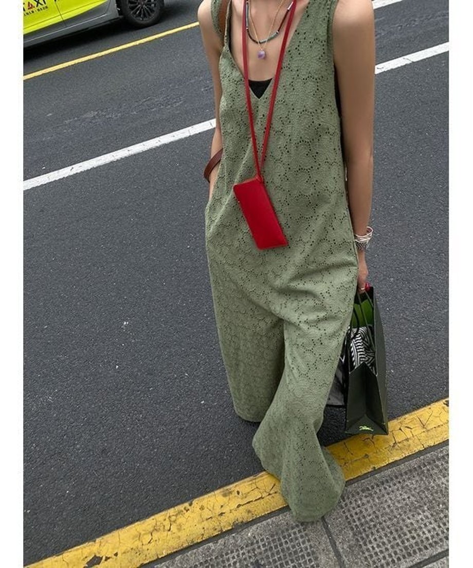 刺繍ジャンプスーツを着用した女性の上から見たアングル。赤い小物を首から下げた屋外ショット。