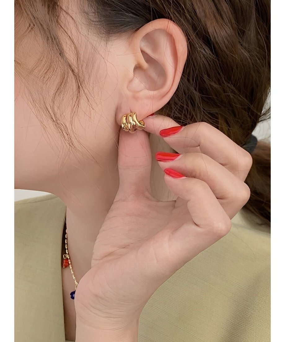 指先に持った、光沢感のあるゴールドの3連ラインデザインピアス