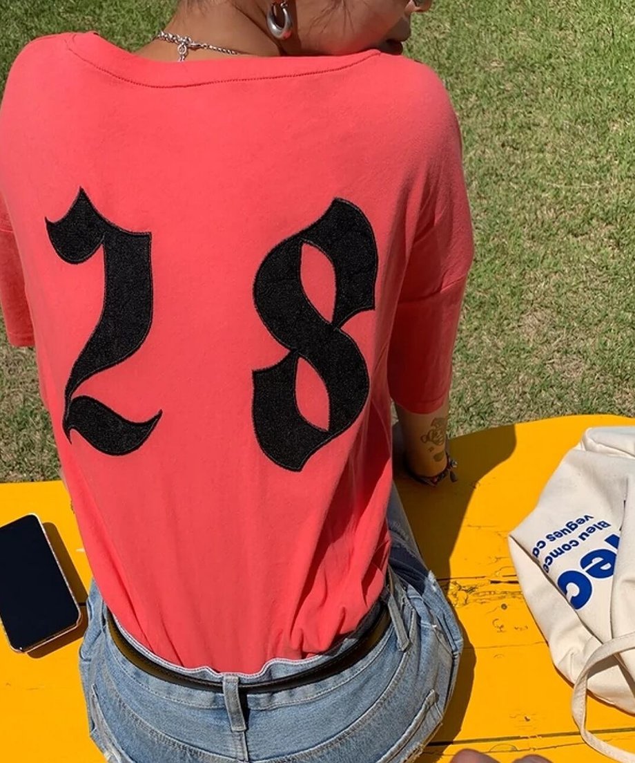 背面に大きな黒い数字の28がデザインされた、ピンクレッドの半袖Tシャツのバックスタイル。