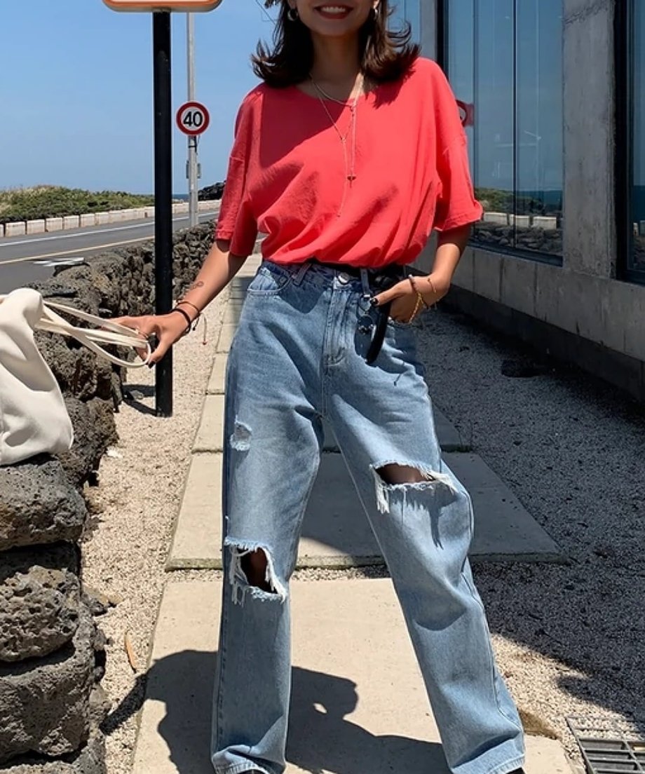 ピンクレッドのルーズTシャツをフロントインして、ワイドデニムと合わせたスタイリッシュな立ち姿。