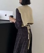 背面リボンが特徴的なショート丈のニットベストを合わせたワンピースのバックスタイル。