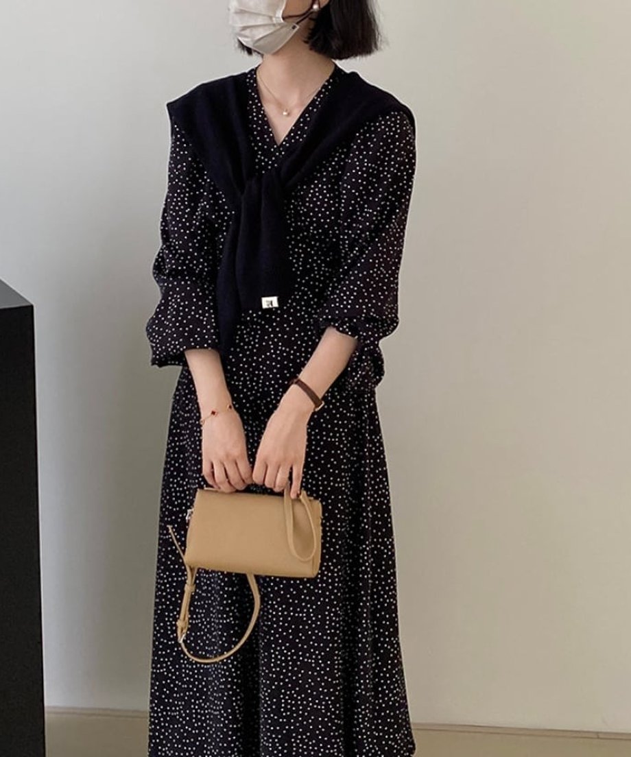細かなドット柄のVネックロングワンピースに黒のカーディガンを肩掛けした女性のコーディネート。