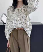 ホワイトの小花柄ブラウスにカーキのタックパンツとブラウンのレザーベルトを合わせた大人のカジュアルコーディネート。