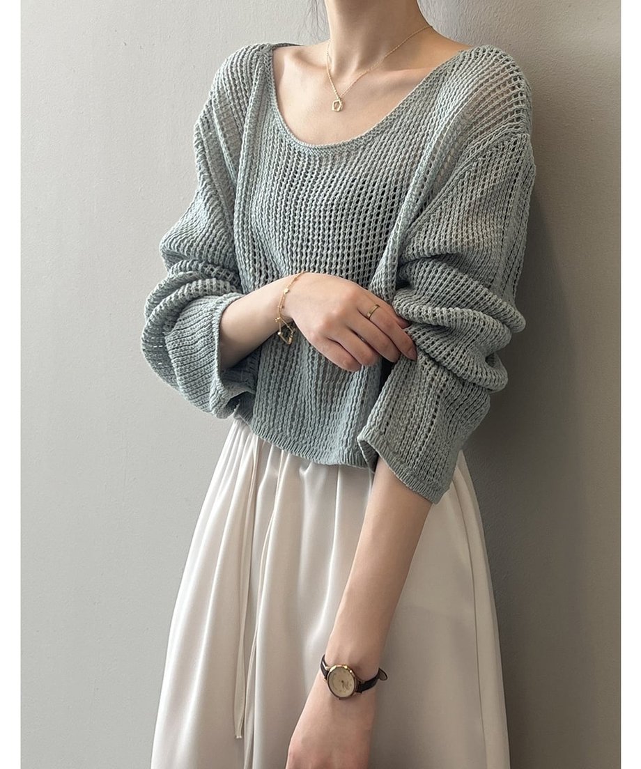 ブルーのメッシュニットを着用し、袖を少したくし上げた女性の斜めからのショット。