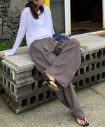 ライトブラウンのワイドパンツをはいた女性がブロックの上に座っている様子。