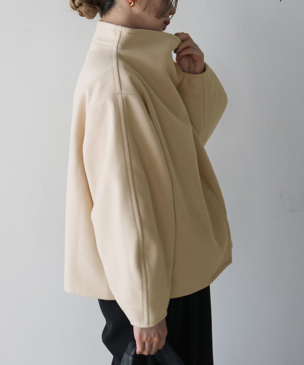 カーキのショートジャケットに黒のパンツを合わせた女性の横向きのスタイル。