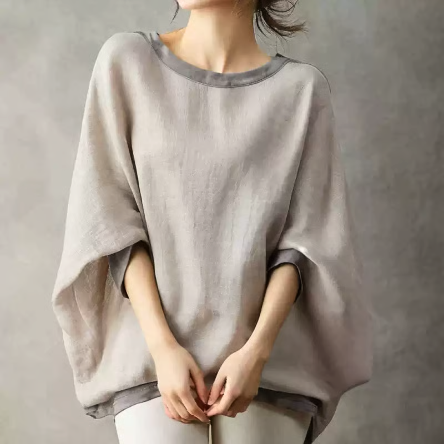 グレージュのプルオーバーを着用した女性、ゆったりとしたシルエットと広めの袖が特徴