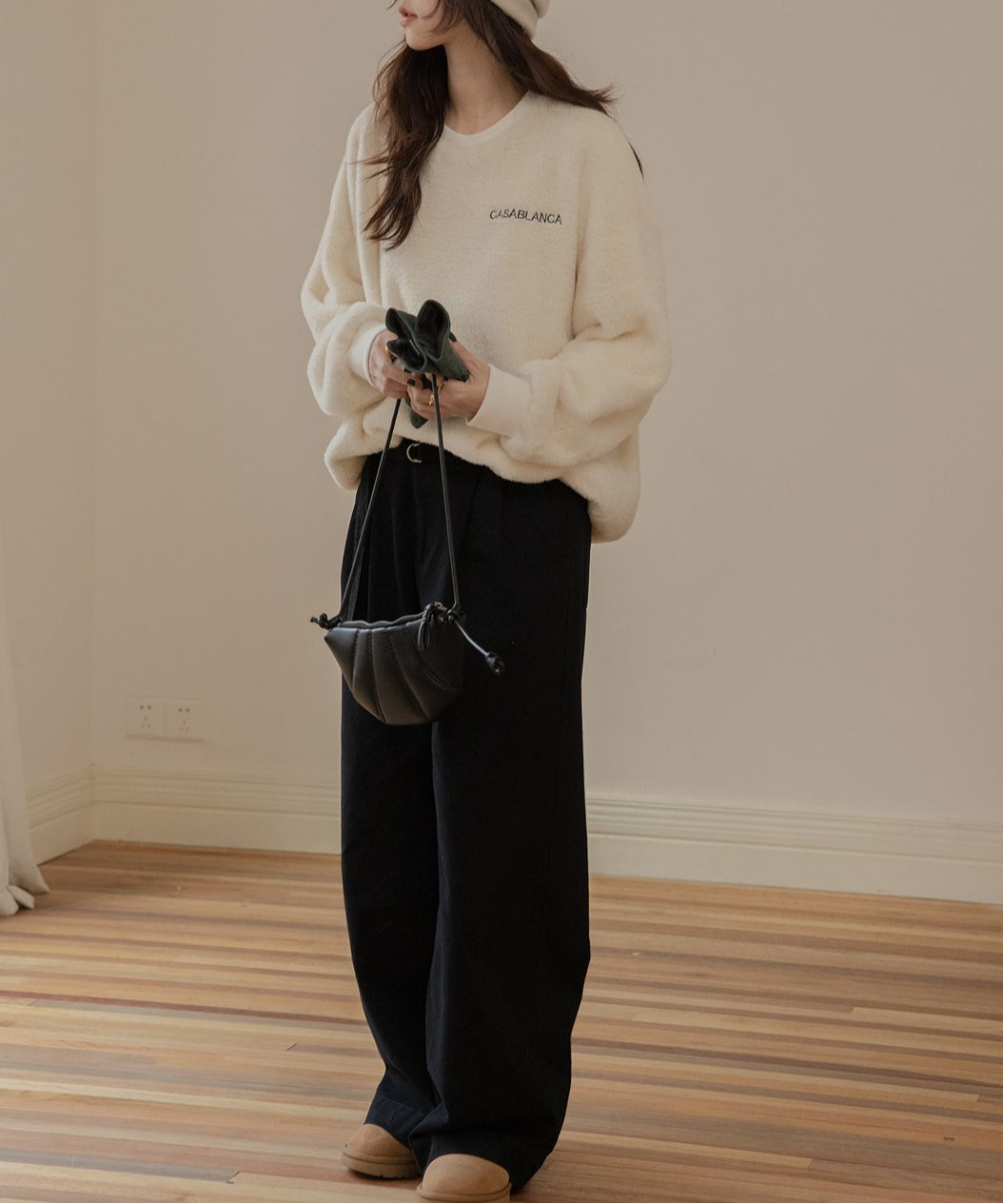 オフホワイトのふわふわしたボア素材のプルオーバーを着た女性のクローズアップ。左胸には「CASABLANCA」の刺繍ロゴが見える。