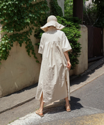 ベージュのリネンドレスワンピースを着た女性が後ろ姿で歩いている様子
