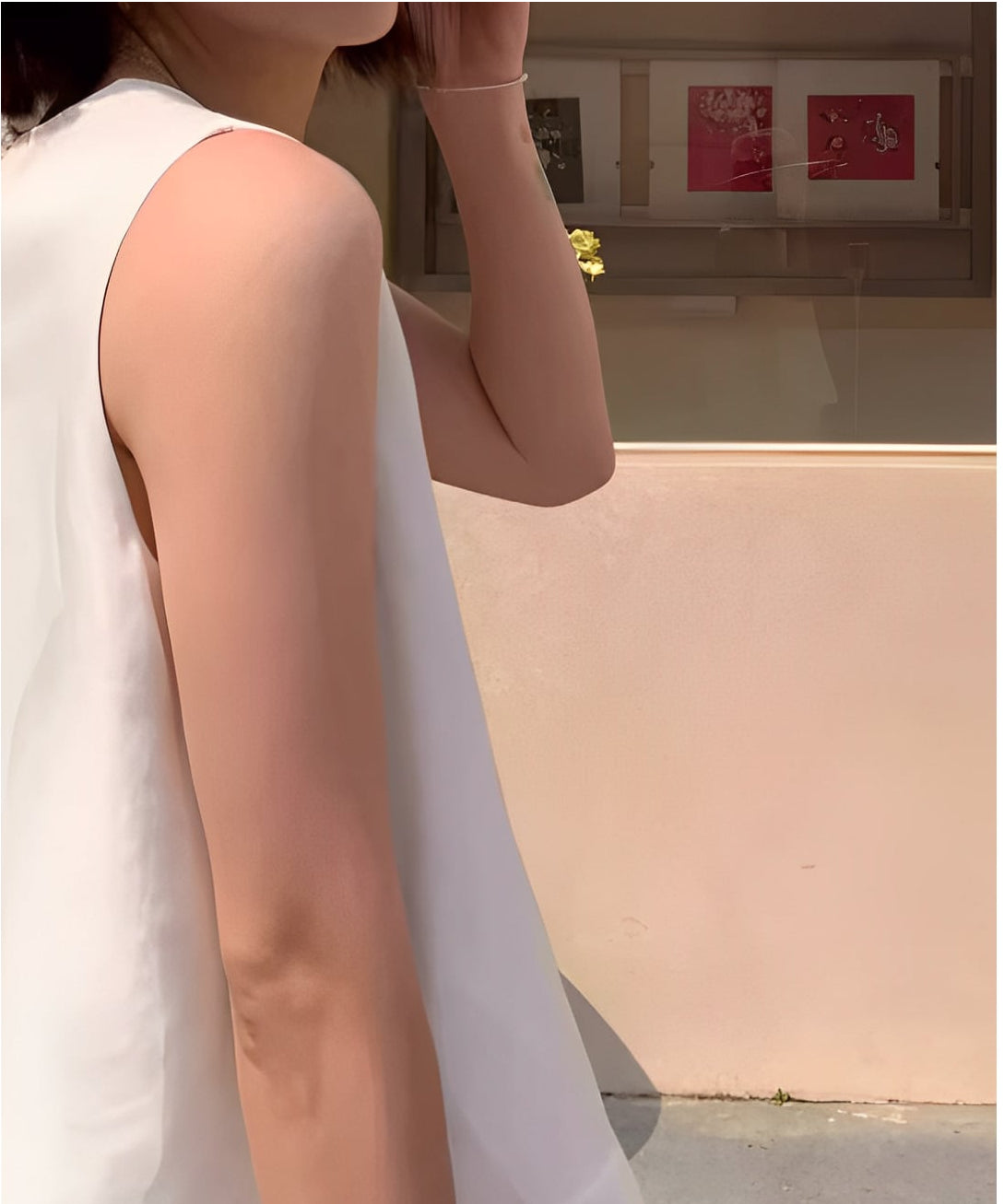 ホワイトのノースリーブトップスを着用した女性の、肩と腕のラインに焦点を当てたクローズアップショット。