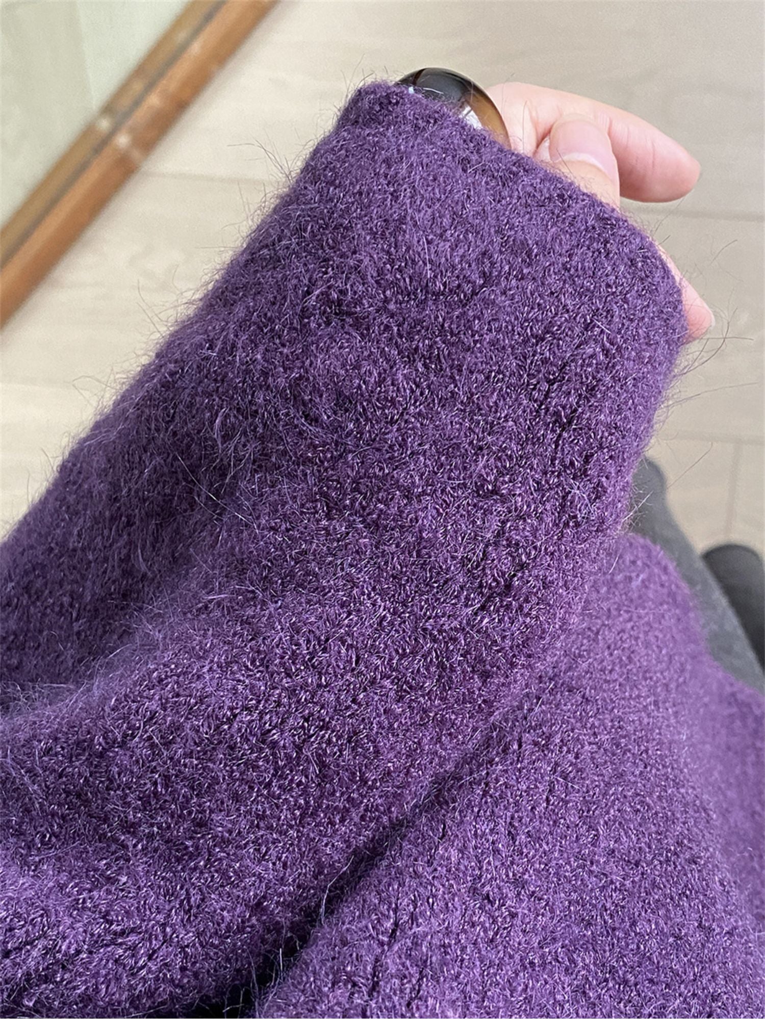 パープルのニットを着用した女性の手元のクローズアップ。