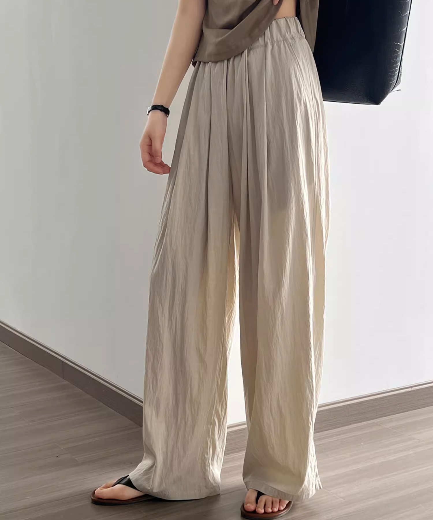 ベージュ色のウエストゴムでシワ加工の施されたワイドパンツを着用した女性。