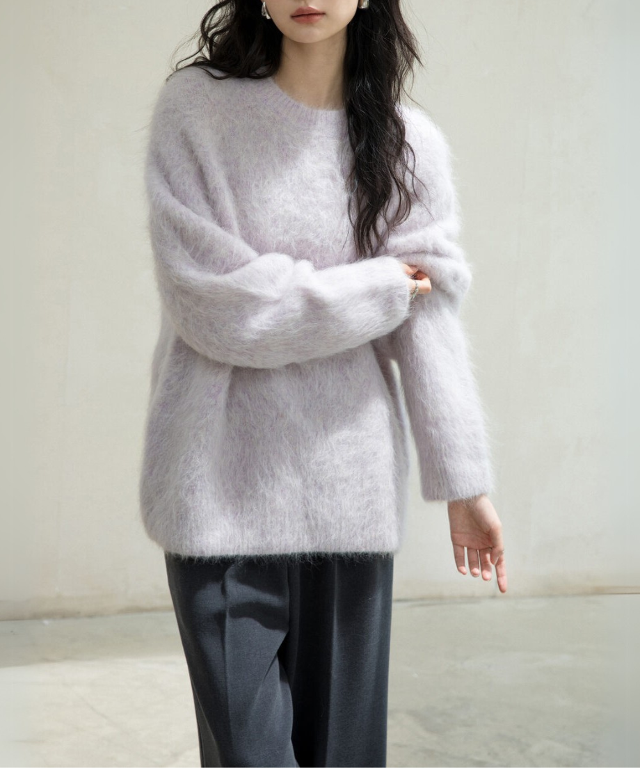 パープル色のふわふわニットを着用し、腕まくりをしている女性のバストアップ。