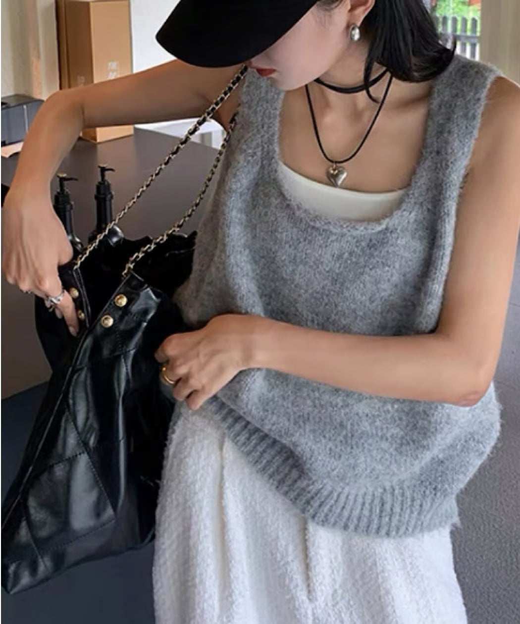 ライトグレー。黒のキャップとバッグを持ち、白いインナーとスカートを合わせている。