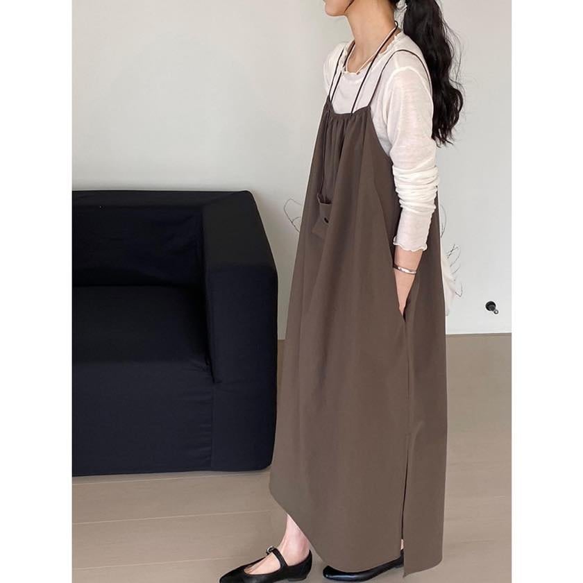 白い長袖トップスに茶色いロングキャミソールワンピースをレイヤードした女性の横からのショット。