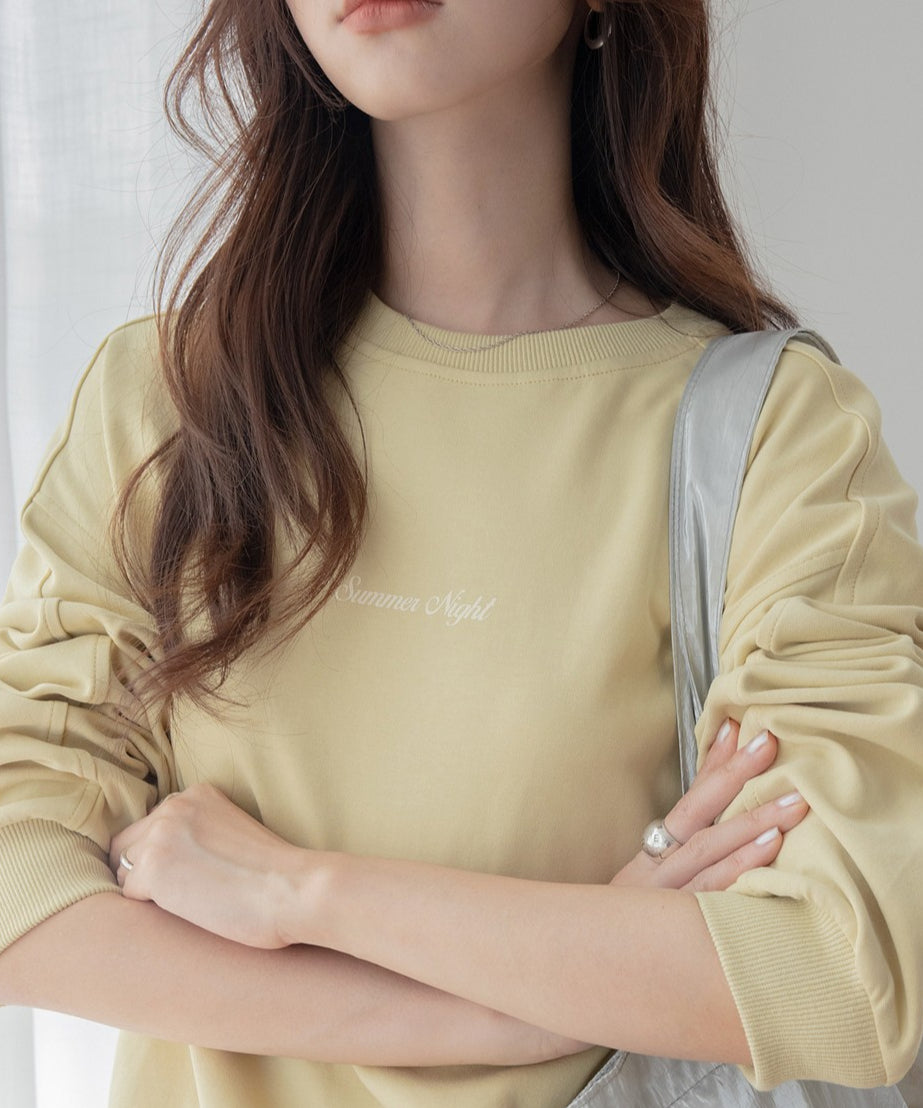 イエローのオーバーサイズスウェットを着用した女性のクローズアップ。女性は淡い色のショルダーバッグを持っている。