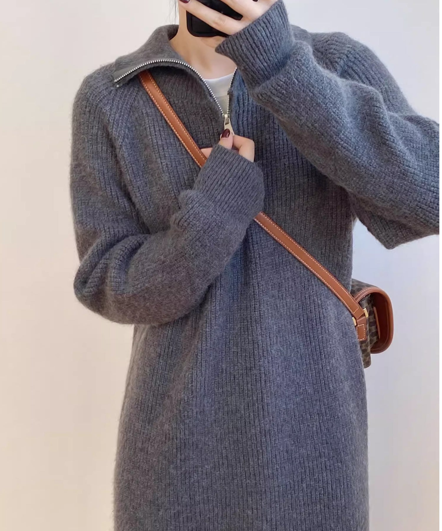 グレーのハーフジップニットロングワンピースを着用し、茶色のバッグを肩にかけた女性の上半身のクローズアップ画像。