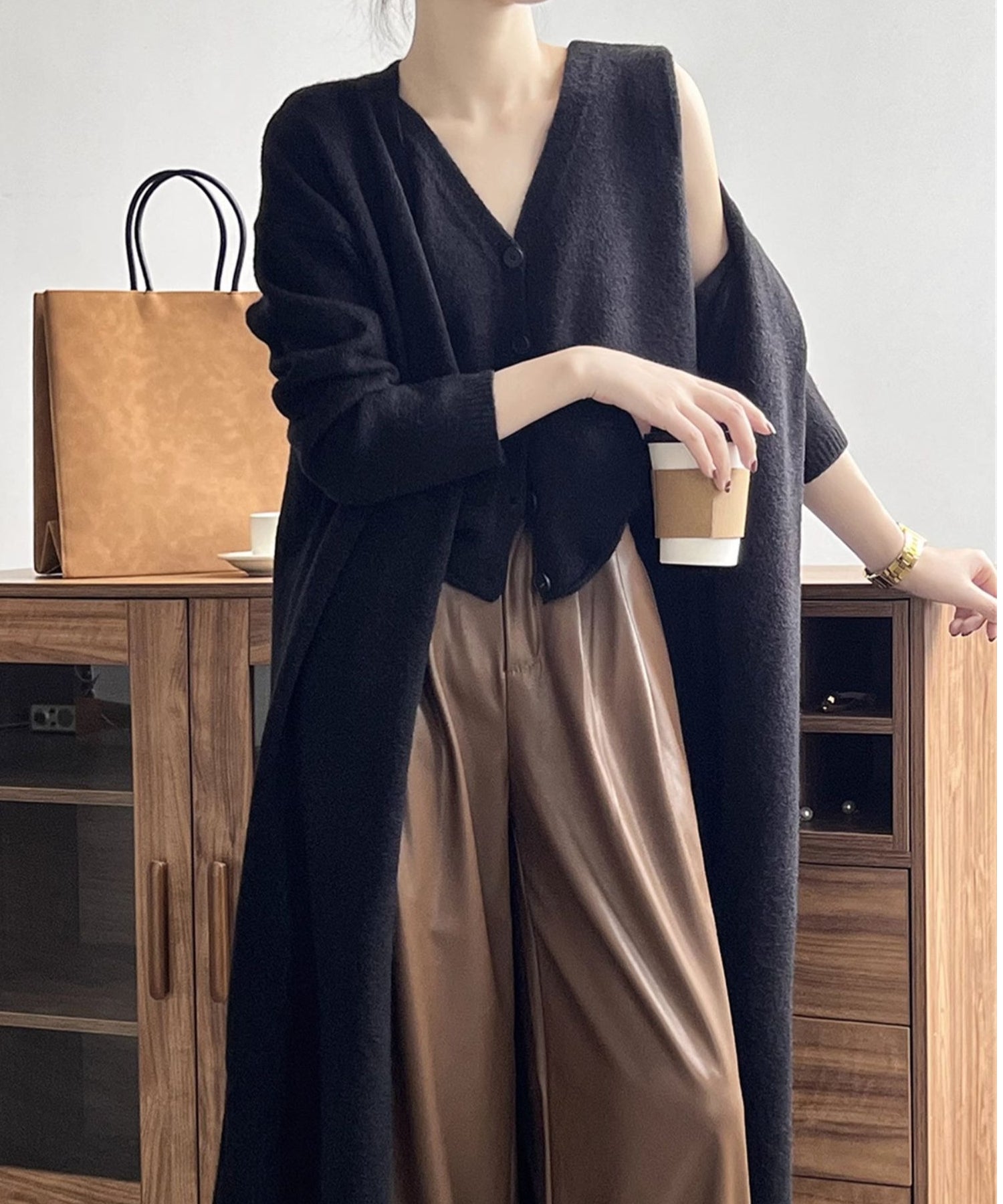 黒のアンサンブルニットを着用した女性が茶系のパンツをはいたショット。
