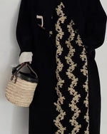 黒のロングダッフルコートの中に花柄のジャンパースカートを着て、籠バッグを持つ女性のアップ画像。